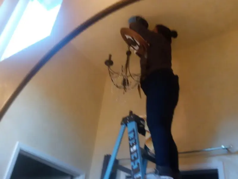 Electrician installing a chandelier in a La Villa residence